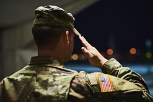 Officer saluting inside a hanger facing the outdoors at night; lawyers specializing in military law near me