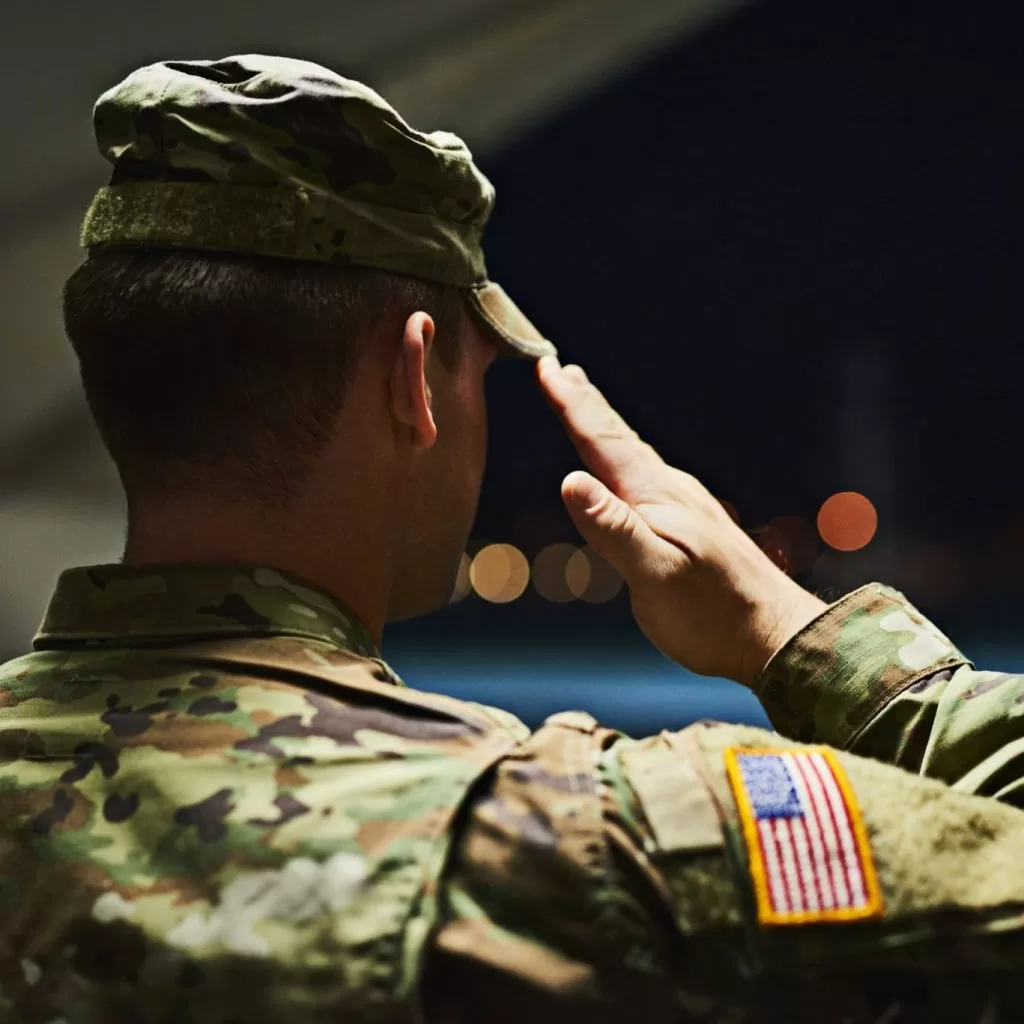 Officer saluting inside a hanger facing the outdoors at night; lawyers specializing in military law near me