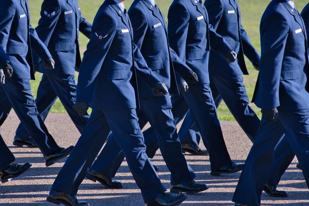 Image shows Air Force basic training graduation parade, new airmen in their dress blues marching in step; USAF discharge rules for sexual offenders; discharge policy sexual offenders